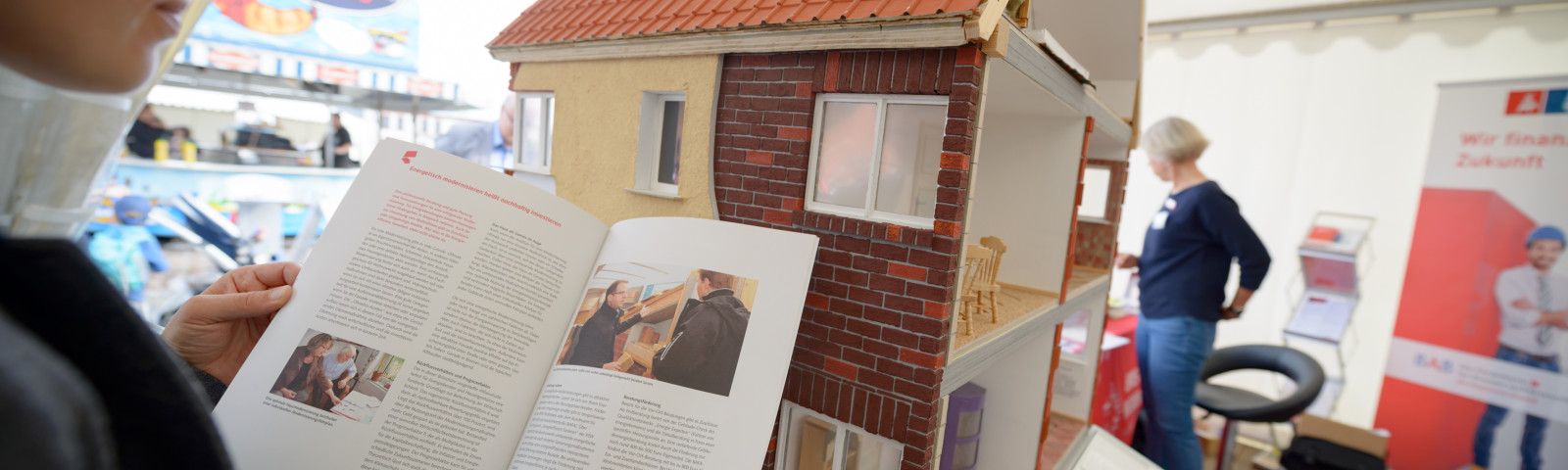 Person liest Broschüre für Modellhaus